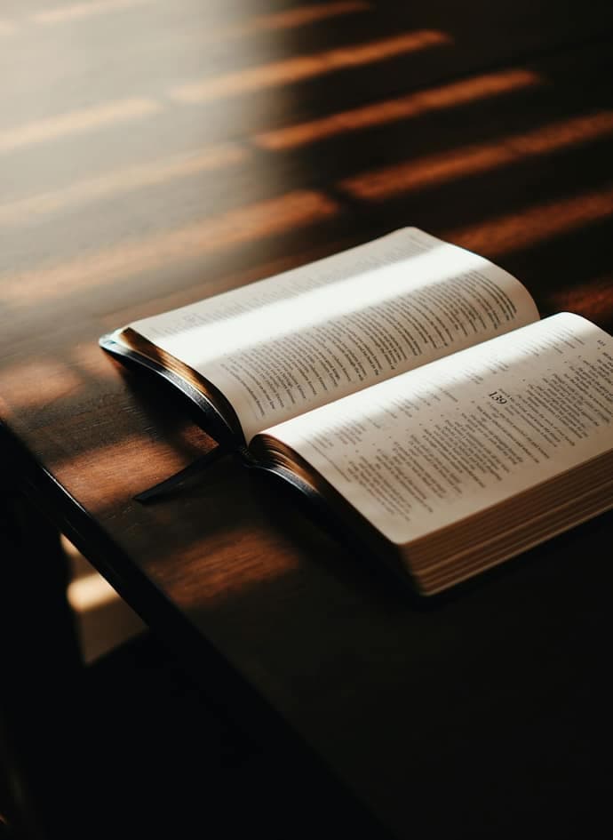 An open book lying on a dark wooden table.