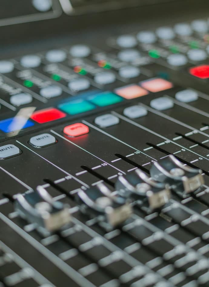 A close-up of a professional audio mixing console with sliders and knobs.