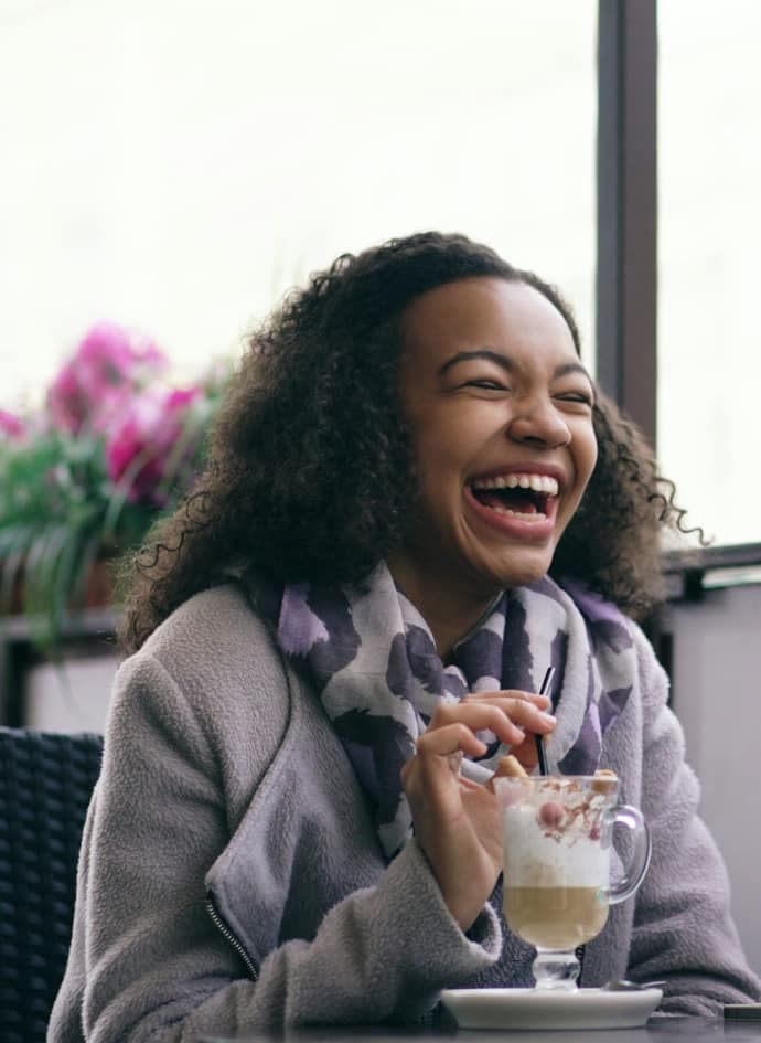 Two women laughing together at a cafe table.