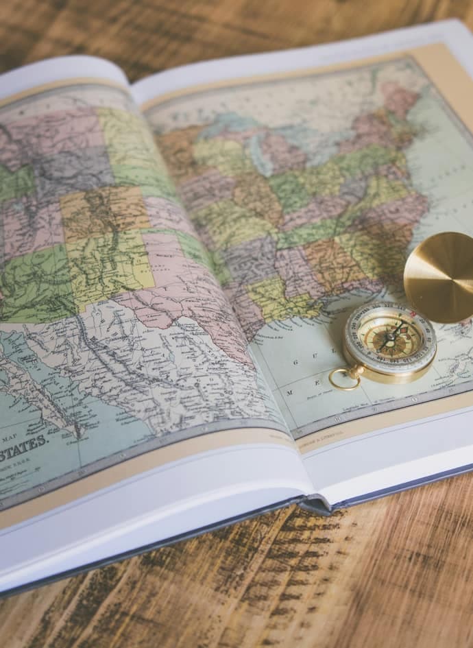 A compass resting on an atlas page.