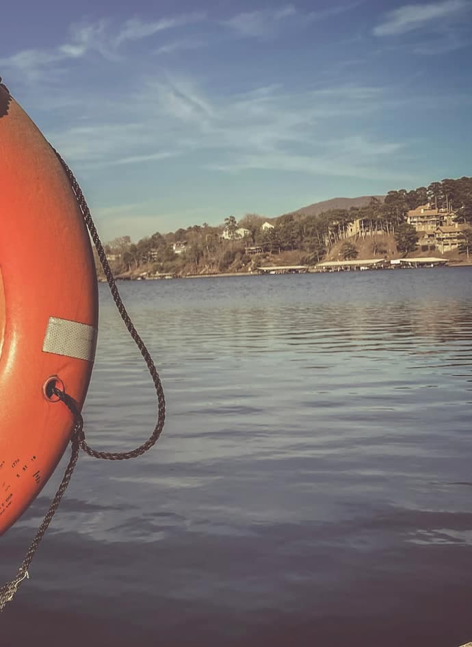 A life preserver on a dock beside the water.