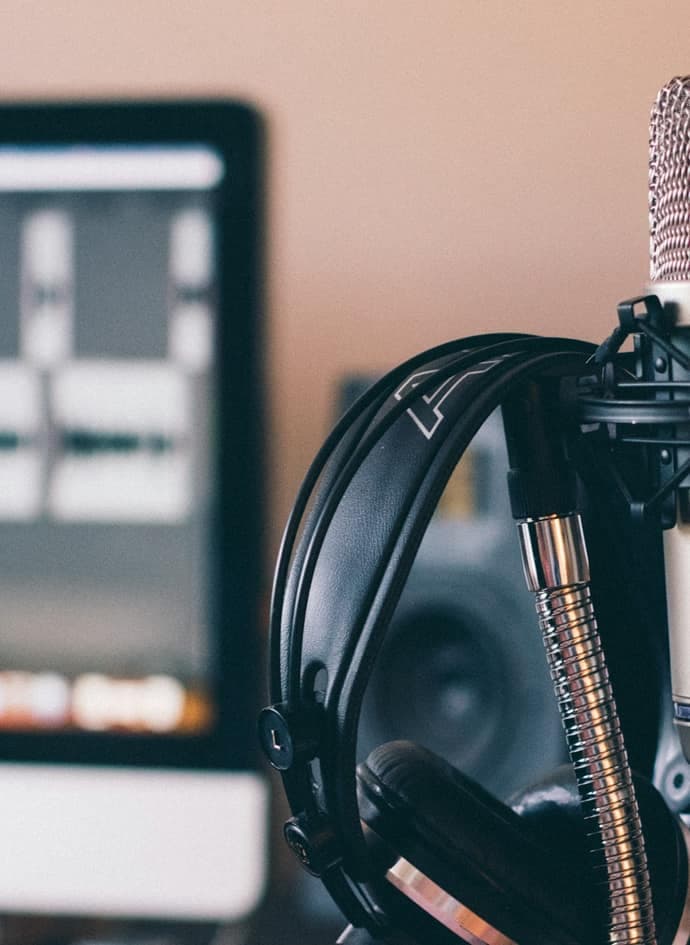 Black and silver headphones resting on a black and silver microphone.