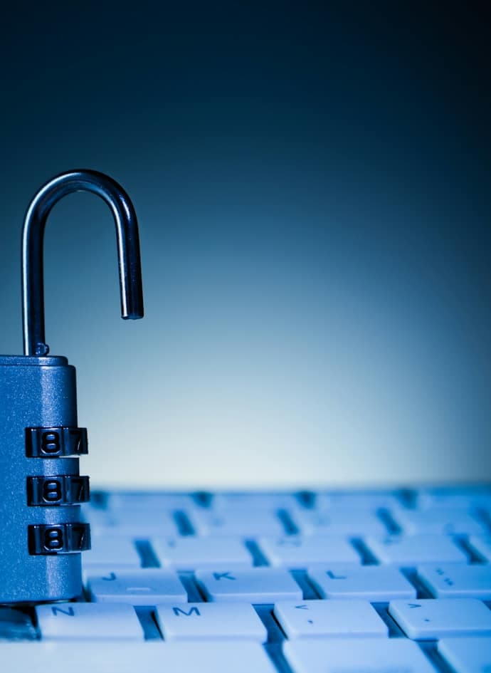 An unlocked padlock resting on a computer keyboard.