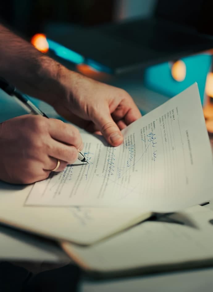 A man signing a document with a pen.